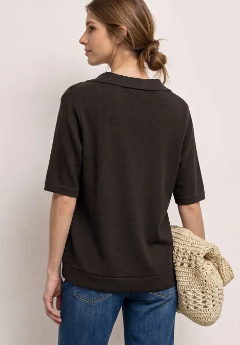 Frau von hinten in dunkelgrauem Poloshirt, Jeans und geflochtener Tasche