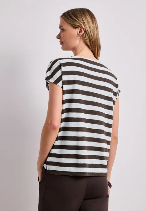 Frau von hinten in gestreiftem Kurzarmshirt und braunen Hosen.