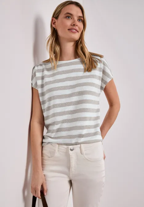 Shirt met hangende schouders, strepen en glitter timeless beige Vrouw in gestreept shirt en lichte broek, staat ontspannen met handen in de zakken.