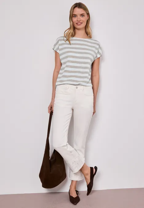 Shirt met hangende schouders, strepen en glitter timeless beige Vrouw in gestreept T-shirt, witte jeans, bruine tas en schoenen, voor een witte achtergrond.