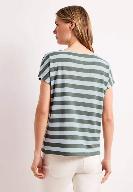 Shirt met hangende schouders, strepen en glitter bound green Achteraanzicht van een vrouw met halflang blond haar, een gestreept shirt en een witte broek voor een lichte achtergrond.