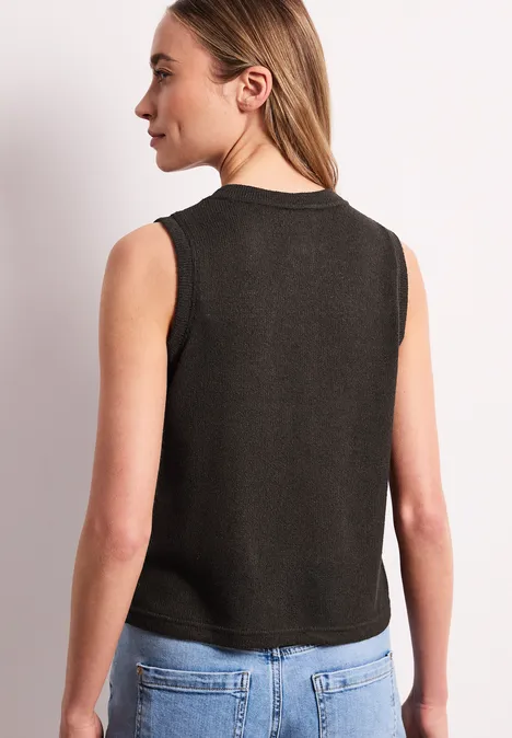 Eine Frau von hinten in schwarzem ärmellosem Top und hellblauen Jeans.