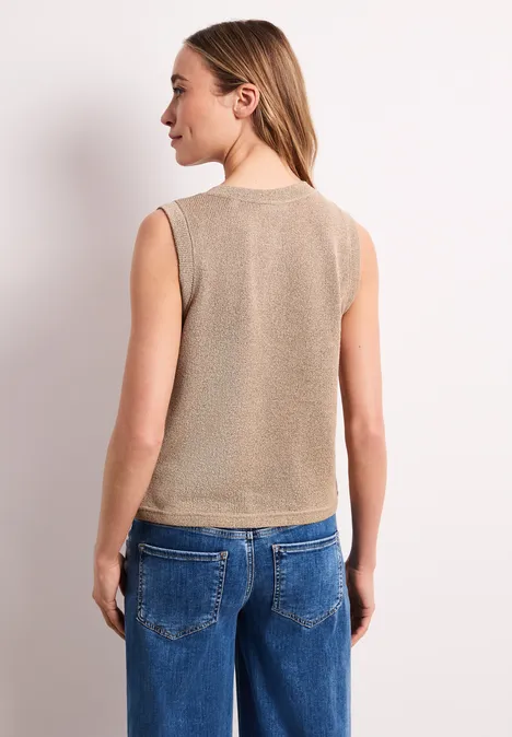 Gebreid gilet met glitter timeless beige Rugaanzicht van een vrouw in een beige mouwloos topje en blauwe jeans.