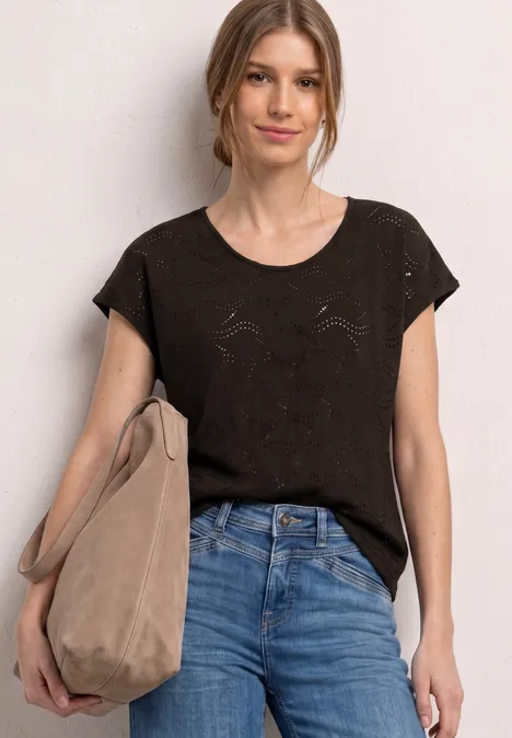 Vrouw met zwart T-shirt, blauwe jeans en een beige tas.
