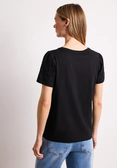 Shirt met ronde hals en kanten mouwen Black Achteraanzicht van een vrouw in een zwart T-shirt met korte mouwen en een lichtblauwe jeans tegen een witte achtergrond.