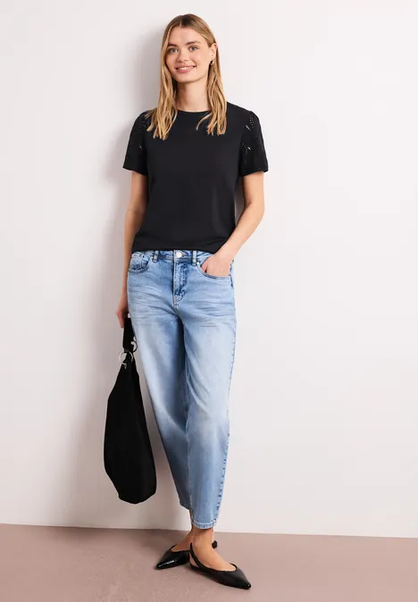 Shirt met ronde hals en kanten mouwen Black Persoon voor lichte achtergrond met zwart t-shirt, wijde spijkerbroek, zwarte ballerinas en tas.