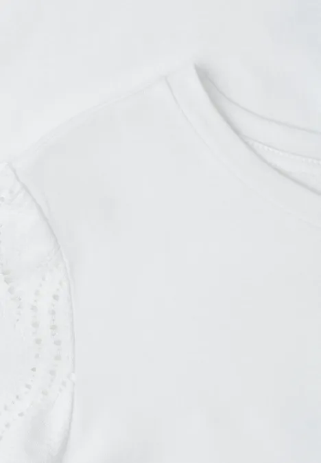 Close-up van een wit kindert-shirt met fijne kanten mouwtjes.