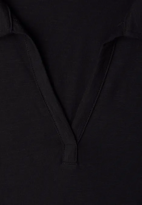 Zwart getextureerd stofdetail met V-hals, vermoedelijk onderdeel van een T-shirt of polo.