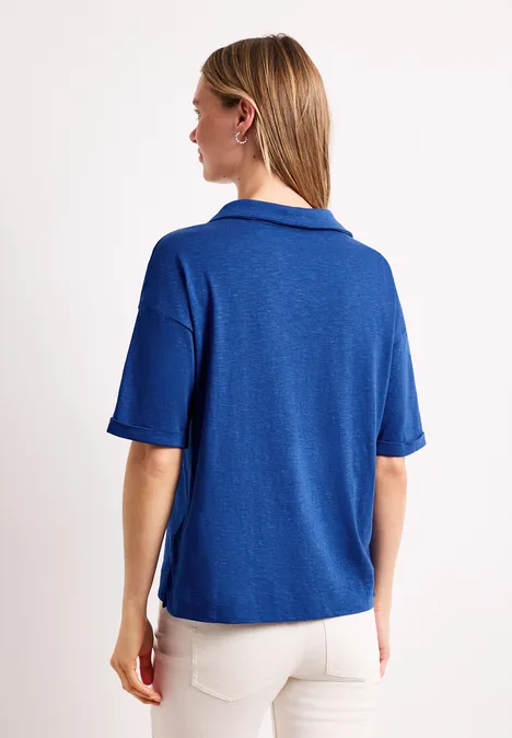 Persoon van achter in een loszittende blauwe polo en witte broek voor een witte achtergrond
