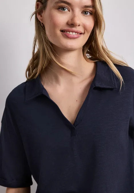 Een lachende vrouw in een marineblauw poloshirt in close-up.