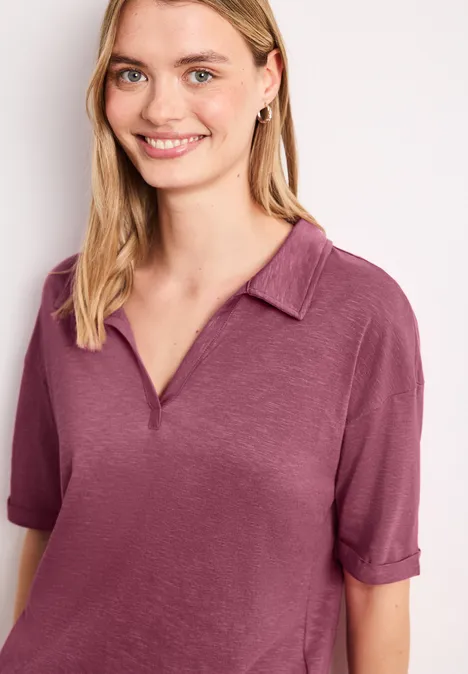 Persoon met wazig gezicht draagt een kort mouwig roze poloshirt met kraag.