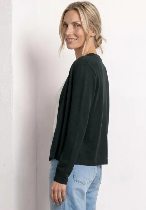 Seitliche Ansicht einer Person mit schwarzem Oberteil und hellblauen Jeans vor weißem Hintergrund.