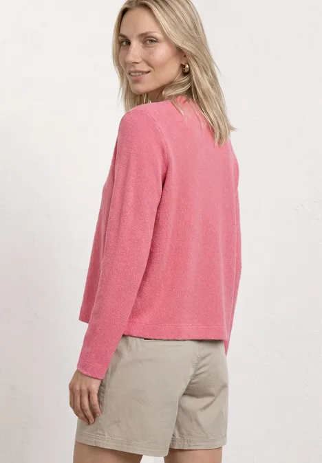 Personne en pull rose et short beige, vue latérale de dos