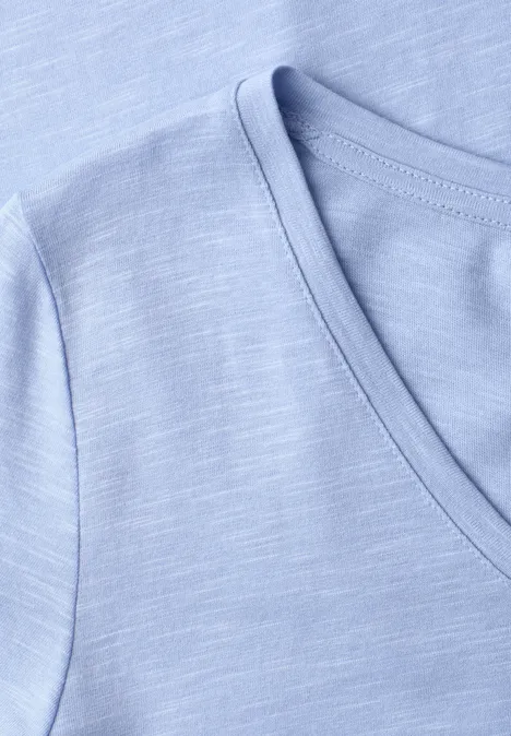 Gros plan sur un t-shirt col V bleu clair à texture subtile
