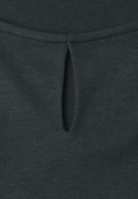 Detailaufnahme eines schwarzen Oberteils mit kleinem tropfenförmigem Ausschnitt und Bügelfalte.