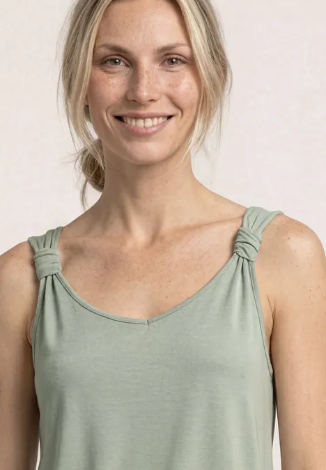 Vrouw draagt een lichtgroen mouwloos topje met gedraaide bandjes en V-hals.
