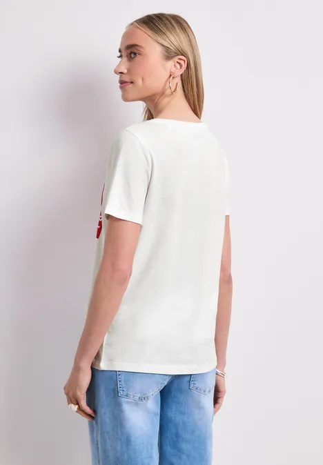 Frau von hinten in weißem T-Shirt und blauer Jeans vor weißem Hintergrund.