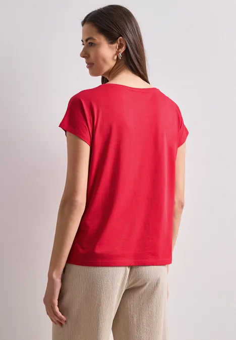 Dropped Shoulder Shirt mit Rundhals salsa red Frau von hinten in schlichter roter Kurzarmshirt und beigen Hosen vor neutralem Hintergrund.