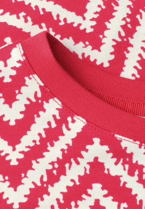Nahaufnahme eines roten Strickshirts mit weißem Zickzackmuster.