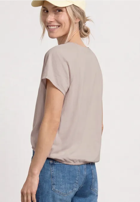 Un mannequin de profil portant un t-shirt beige et un jean bleu sur fond blanc