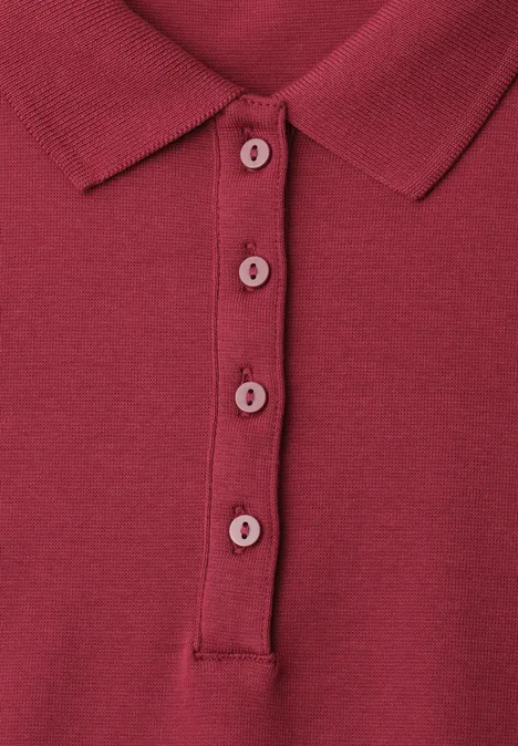 Close-up van een bordeauxrood poloshirt met omgeslagen kraag en vier knopen