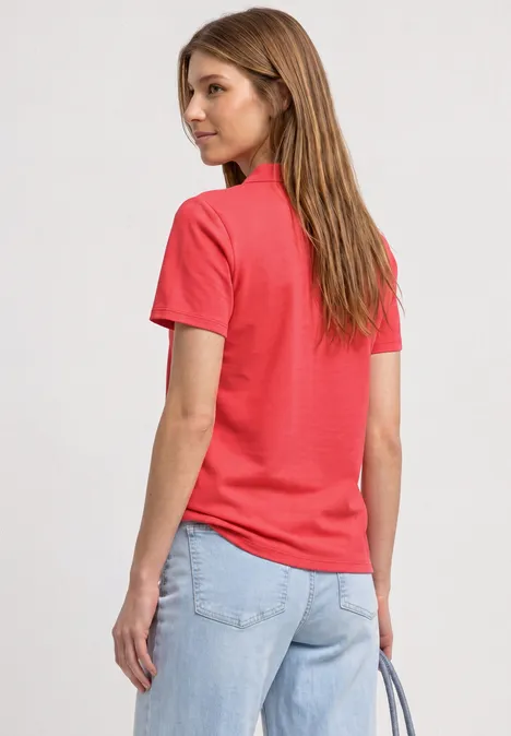 Kurzarm Poloshirt in Rippstruktur sunset red Frau von hinten in rotem T-Shirt und hellblauen Jeans, trägt Handtasche.