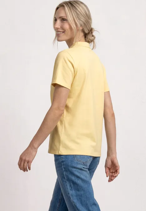 Rückenansicht einer Person in gelbem T-Shirt und blauen Jeans, entspannte Pose.