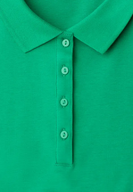 Close-up van een groen poloshirt met knoopsluiting en bijpassende knopen