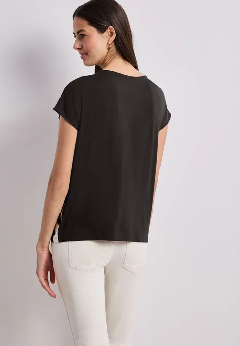 Vrouw van achteren met een zwart shirt en witte broek.