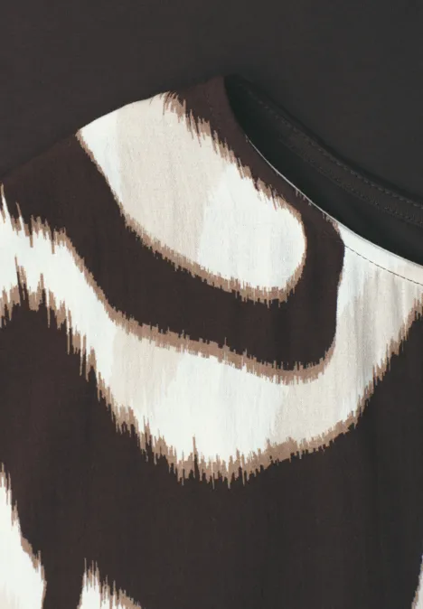 Close-up van stof met onregelmatige bruine en roomkleurige strepen op een lichte achtergrond.