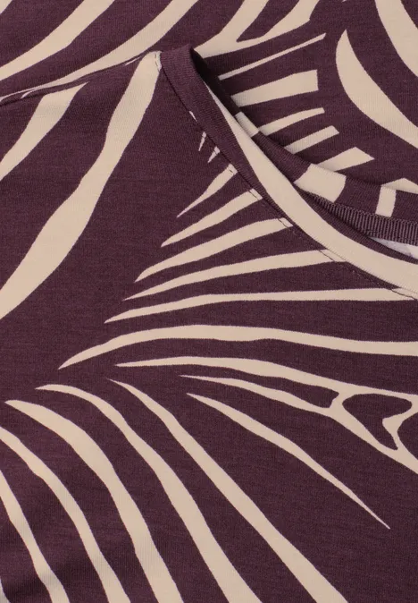 Nahaufnahme eines violetten Shirts mit cremefarbenem, abstraktem Zebramuster.