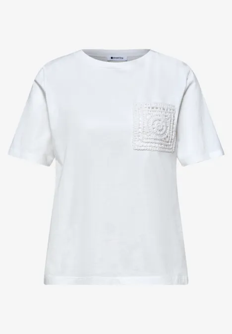 Witte T-shirt met ronde hals en een borstzakje versierd met gehaakte kant.