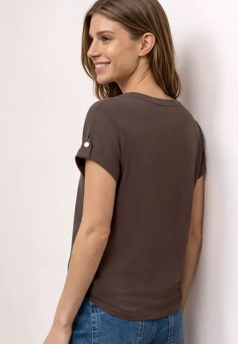 Frau von hinten in braunem T-Shirt und Jeans, mit schulterlangen Haaren