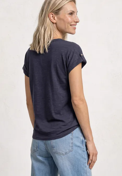 Shirt met gespleten hals en knoopdetails shadowed navy Een vrouw van achteren in een donkerblauw T-shirt en lichte jeans, voor een lichte achtergrond.