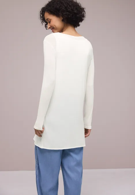 Persoon van achteren in wit lang shirt en losse lichtblauwe broek.