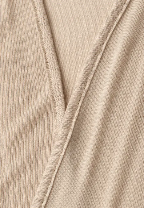 Detailopname van een beige gebreid stof met V-naad.