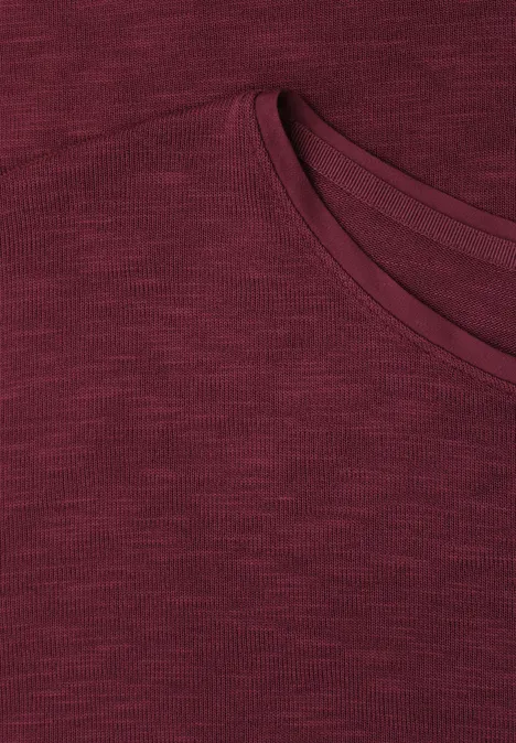 Close-up van een donkerrood T-shirt met ronde hals en subtiel gemêleerde stof.