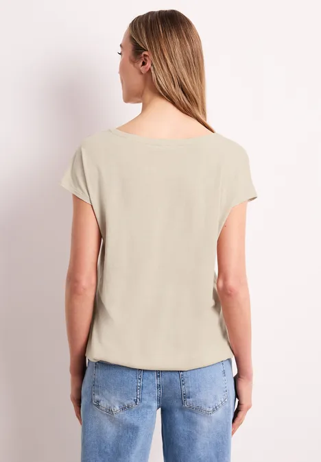 Vrouw van achter gezien met een beige top en blauwe jeans.