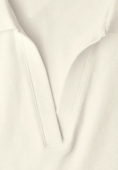 Helles beige Kleidungsstück mit V-förmigem Ausschnitt und feinen Nahtdetails.