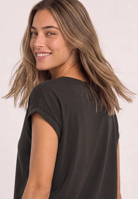 T-Shirt mit Boatneck und Deko-Tape espresso brown Eine lächelnde Frau im schwarzen Shirt schaut über die Schulter vor hellem Hintergrund.