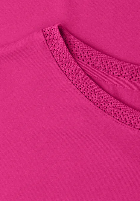 Nahaufnahme eines pinkfarbenen T-Shirt-Ausschnitts mit feinem Stoff und Ziernähten