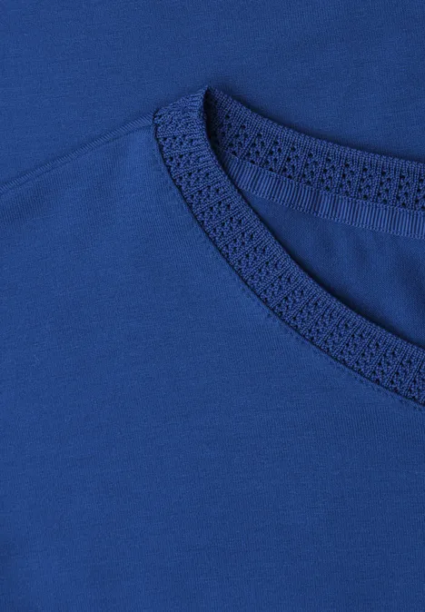 Nahaufnahme eines blauen T-Shirts, Fokus auf den Rundhalsausschnitt und Materialstruktur.