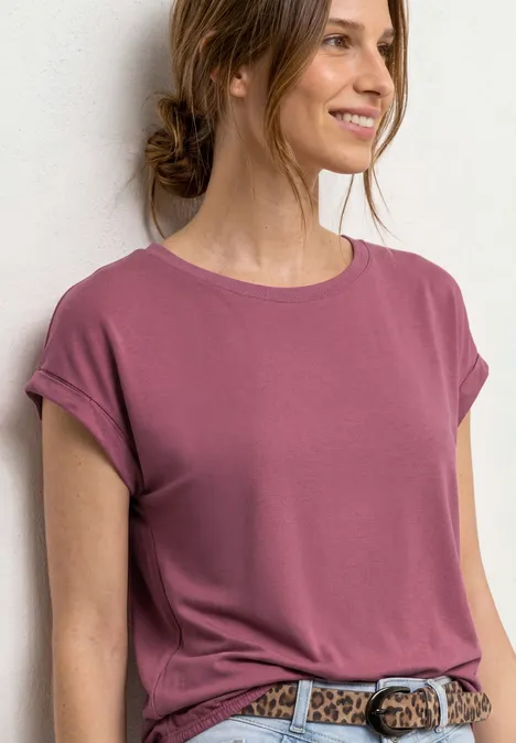 Frau trägt locker sitzendes rosa T-Shirt mit hochgekrempelten Ärmeln und Leopardenmuster-Gürtel.