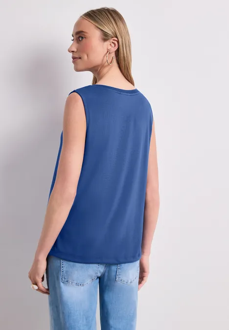 Top im U-Boot-Ausschnitt amparo blue Frau von hinten in blauem, ärmellosem Oberteil und Jeans