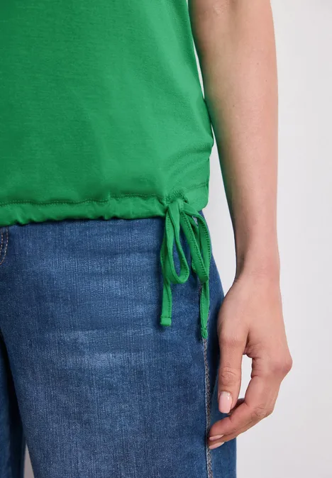 Top im U-Boot-Ausschnitt ever green Teilansicht einer Person in grünem Top und Jeans mit sichtbarer Hand am Oberschenkel.