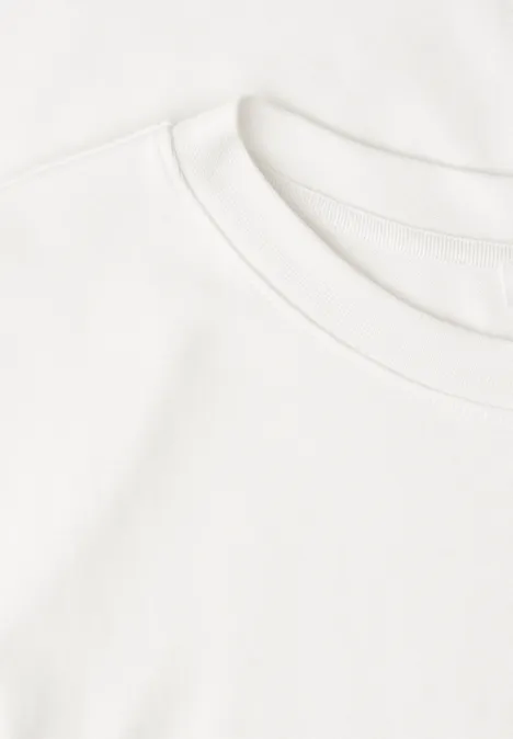 Twee gestapelde witte T-shirts op een lichte ondergrond