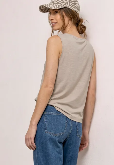 Vrouw van achteren in een beige top en blauwe jeans, gezicht onscherp.