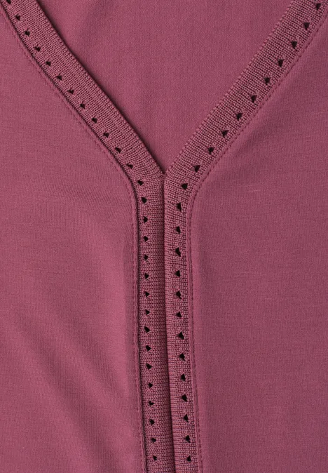 Nahaufnahme eines rosafarbenen Oberteils mit V-Ausschnitt und Zierlochstickerei