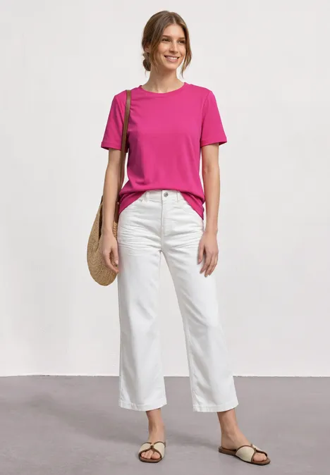 T-Shirt mit gerafftem Ärmel magenta dream Frau in pinkem T-Shirt, weißer Hose, Sandalen und Umhängetasche vor neutralem Hintergrund.