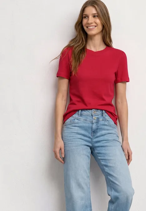 T-Shirt mit gerafftem Ärmel salsa red Frau in rotem T-Shirt und blauen Jeans steht vor hellem Hintergrund.